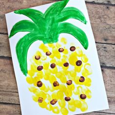 a pineapple painted on white paper with yellow dots and green leaves in the center