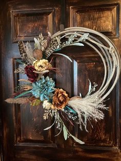 a wreath with feathers and flowers on the front door