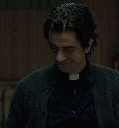 a man wearing a priest's outfit in a dark room