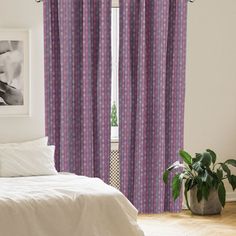 a bed room with a neatly made bed and a window covered in purple patterned curtains