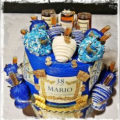 a blue and white cake with gold trimmings on the top is surrounded by confections