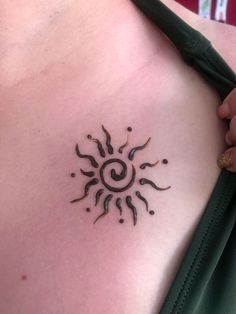 a tattoo on the back of a woman's chest with sun and spirals