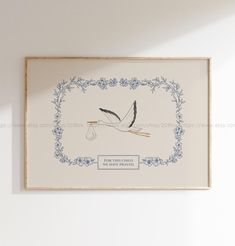 a stork carrying a baby in a bag is hanging on the wall next to a frame