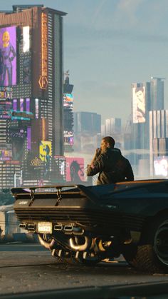 a man sitting on top of a car in the middle of a city with tall buildings