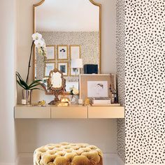 a vanity with a stool, mirror and pictures on the wall in front of it