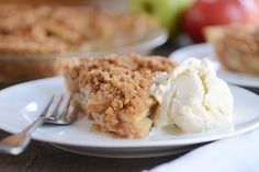 a piece of pie on a plate with ice cream and an apple in the background