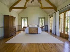 a large bedroom with wood floors and white walls