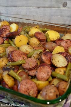 a skillet filled with sausage, corn and vegetables on top of a wooden table