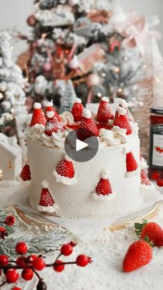 a white cake topped with strawberries on top of a table next to a christmas tree