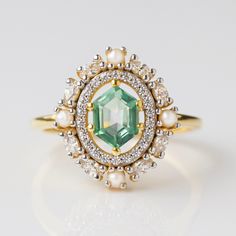 an emerald and white diamond ring with pearls