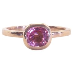 a gold ring with a pink stone in the center and a thin band around it