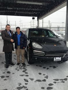 two people standing next to a car in the snow