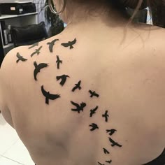 the back of a woman's shoulder with birds flying around her and in the air