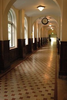 the hallway is lined with arched windows and checkered flooring, along with clock