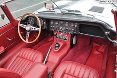 the interior of an old car with red leather seats and dash board, steering wheel and dashboard