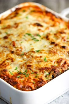 a casserole dish with meat and cheese in it sitting on a cloth covered table