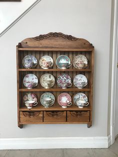 a wooden shelf filled with lots of china on top of a white wall next to a stair case