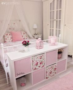 a white and pink bedroom with flowers on the dressers, bedding and pillows