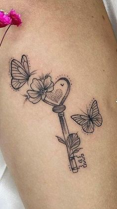 a woman's thigh with a key tattoo on it and butterflies flying around her