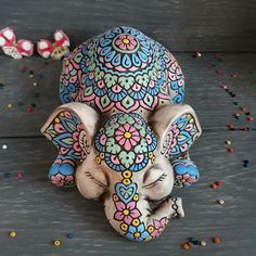 an elephant figurine with colorful designs on it's face and trunk sitting next to confetti sprinkles