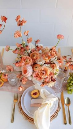 the table is set with peach colored flowers and place settings for an elegant dinner party