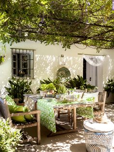 an outdoor dining area with green and white table cloths, chairs, and potted plants