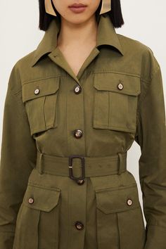 Elevate Your Outerwear With This Cargo Style Jacket, Featuring A Longline Length Cut By A Buckle Belt For A Cinched Waist And Peplum Style Effect. Finished With Contrasting Button Detailing That Adorns Top And Bottom Flap Pockets And A Button Down Design. Finished With A Collared Neckline And Long Sleeves.Cargo Jacketbeltedlong Length Green Utility Jacket With Flap Pockets For Work, Olive Utility Jacket For Fall Workwear, Green Long Sleeve Outerwear With Belted Cuffs, Green Outerwear With Belted Cuffs And Long Sleeves, Belted Utility Jacket For Work, Green Utility Jacket With Lapel Collar For Workwear, Olive Workwear Outerwear With Flap Pockets, Khaki Collared Utility Jacket For Work, Olive Utility Jacket For Spring Workwear