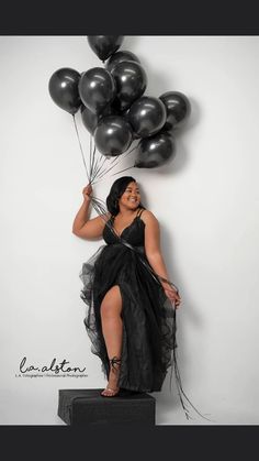 a woman in a black dress is holding balloons and posing for the camera with her legs crossed