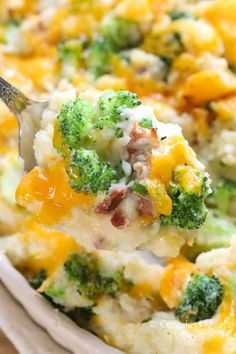 a spoon full of broccoli casserole with cheese and other toppings