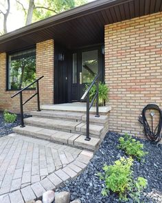 a brick house with steps leading up to the front door and entry way that has black iron handrails