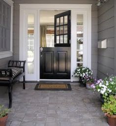 the front door is black and there are flowers in pots