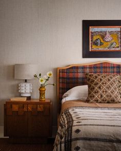 a bedroom with a bed, nightstand and painting on the wall above it's headboard