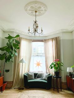 a living room filled with furniture and a chandelier hanging from the ceiling next to a window