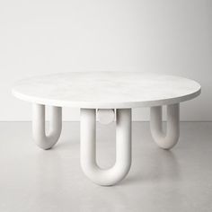 a white table sitting on top of a cement floor next to a wall with two hooks hanging from it's sides