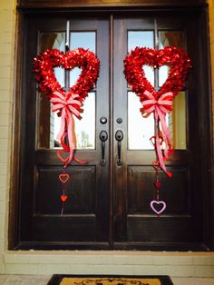 two heart shaped wreaths are hanging on the front door