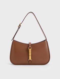 This product is made with at least 20% sustainable materials by weight. CHARLES & KEITH uses recycled, degradable, organic, and water-based materials in our eco-conscious collection. The Cesia minimalist design enhances its versatility, making it the perfect style companion for office hours, casual weekends, and everything in between. With its timeless combination of chocolate brown and metallic gold, it will add a touch of elegance to your everyday wardrobe, effortlessly elevating any look. The metallic gold accent serves not only as a decorative element but also as a functional magnetic closure, ensuring the safety and security of your personal belongings. Handbags Charles And Keith, Everyday Brown Bag, Purse Dump, Charles And Keith Bags, Charles And Keith, Vetements Clothing, Accessorize Bags, Dream Bags, Brown Purse