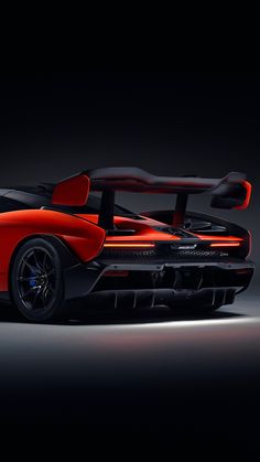 an orange and black sports car is shown in the dark room with its doors open