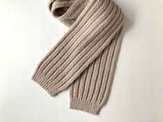 a knitted scarf laying on top of a white surface