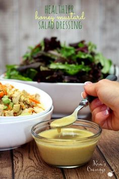 someone is dipping dressing into a salad in a bowl