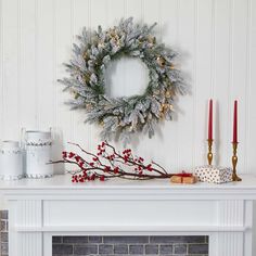 a wreath and candles on a mantle in front of a fireplace with other holiday decorations