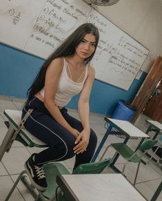 a woman sitting on top of a desk in a classroom