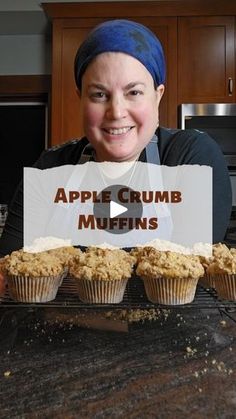 a woman holding up a sign with muffins in front of her and the words apple crumb muffins on it