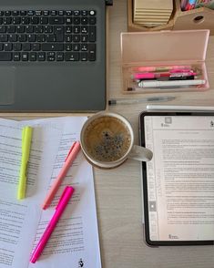 a laptop computer sitting on top of a wooden desk next to a cup of coffee