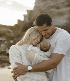 a man and woman holding a baby on the beach