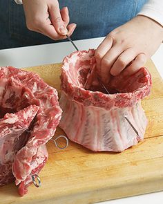 a person cutting meat with a pair of scissors on a cutting board in front of them