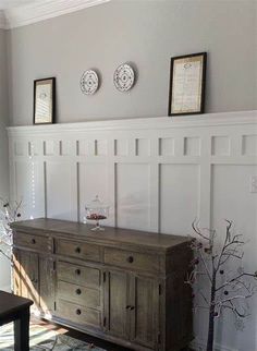 a living room with a large wooden dresser next to a tree and two pictures on the wall