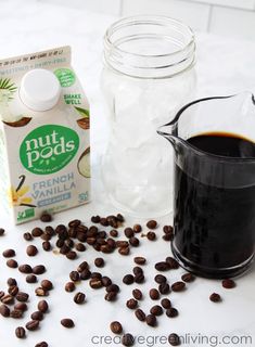 a glass pitcher filled with coffee next to a carton of nut pods