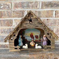 a wooden nativity scene with figurines in the mangeracle, on a brick wall