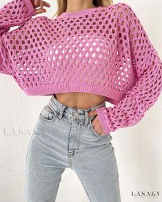 a woman wearing a pink sweater with holes on the front and bottom, posing for a photo