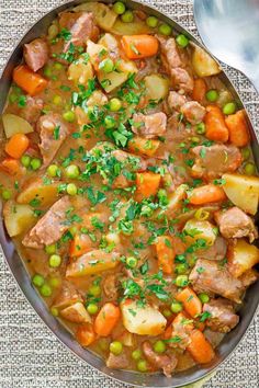 a bowl filled with meat and vegetables on top of a table next to a spoon